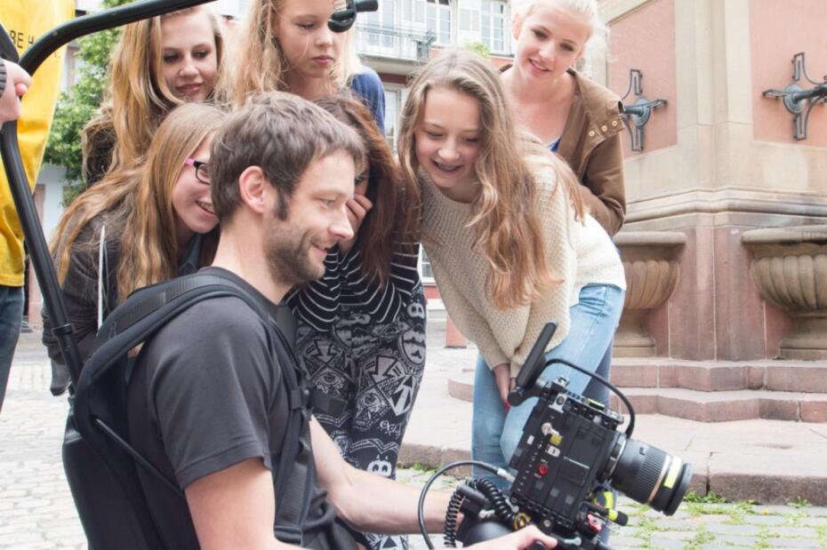 Tänzerinnen und Videoteam stehen um den Monitor herum